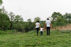 Happy family mother father and child son on nature on sunset. Mom, Dad and kid laughing and hugging, enjoying nature outside. Sunny day, good mood. concept of a happy family. photo