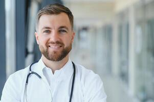 retrato de un masculino médico en pie en un hospital corredor. foto
