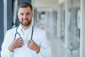 Portrait of handsome young doctor on hospital corridor photo