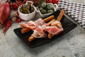 Antipasti - Grissini with pork bacon photo