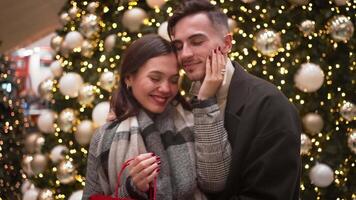 Romantic couple kissing and embracing near decorated Christmas tree video
