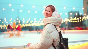 mujer en calentar ropa sonriente a cámara fuera de hielo pista durante Navidad video