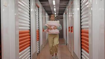 mulher com dela coisa caminhando dentro auto armazenamento unidade video