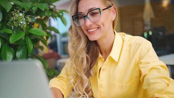 sonriente mujer de negocios utilizando ordenador portátil a acera café mesa video