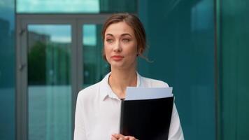 retrato de confidente mujer de negocios con carpeta documento caminando fuera de oficina video