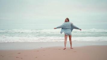 travel concept Happy woman running ocean beach and turns around dressed denim shirt video