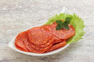Sliced pepperoni sausage in the bowl photo