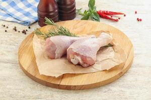 Raw chicken leg over board photo