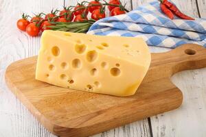 Maasdam cheese piece over board photo