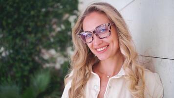 a woman with glasses smiles at the camera video