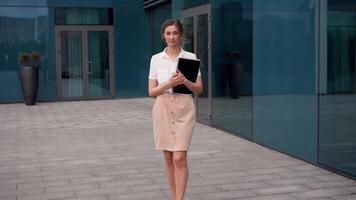 un mujer es en pie en frente de un edificio participación un libro video