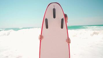 a woman is standing on the beach holding a surfboard video