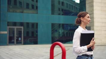un mujer es en pie en frente de un edificio participación un libro video