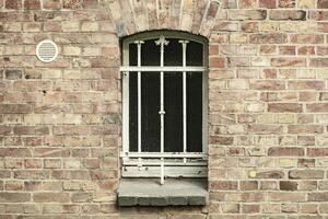 barred cellar window in a brick wall photo