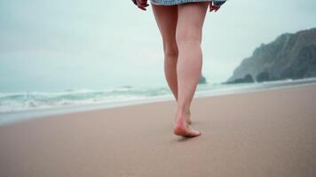 Cheerful young woman running on sandy beach by sea at autumn video