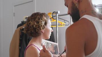 gay homem com tatuagem aplicando Maquiagem em mulher dentro estúdio video