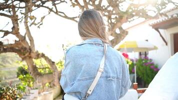 Smiling young woman standing outside white house in countryside rear view video