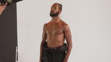 Shirtless gay man posing for professional photographer in studio video