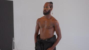 Artist photographing shirtless African-American gay man with makeup in studio video