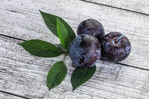 crudo púrpura ciruelas montón con hojas foto