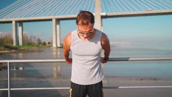 a man in sunglasses standing on a pier near the water video