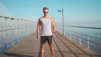 un hombre en Gafas de sol en pie en un muelle cerca el agua video