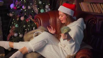 a woman in a christmas hat sitting on a chair near a fireplace video