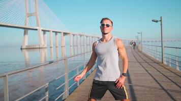 ein Mann im Sonnenbrille Stehen auf ein Seebrücke in der Nähe von das Wasser video