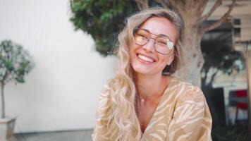 portrait une femme avec des lunettes est souriant et à la recherche à le caméra video