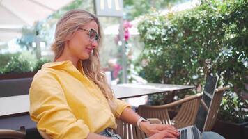 a woman in glasses sitting in a cafe with a laptop video