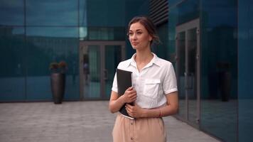 un mujer en un negocio traje participación un carpeta video