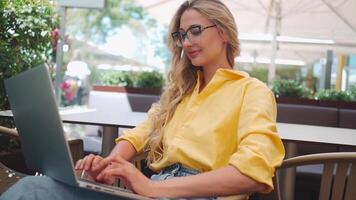 a woman in glasses sitting in a cafe with a laptop video