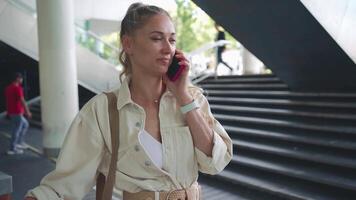 un mujer en un blanco camisa hablando en un célula teléfono video