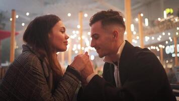 romantisch Datum von jung zärtlich Paar halten Hände und Reiben Nasen Sitzung beim Cafe Tabelle Gesicht zu Gesicht. video