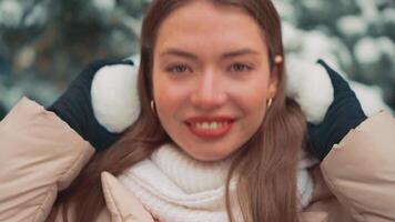 Close up portrait young woman with fur earmuffs winter day outdoor. video