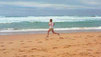 Drone aerial footage slim blonde woman running ocean beach. video