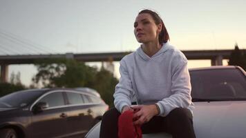 une femme séance sur le capuche de une voiture video