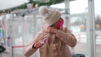 a woman in a pink coat and a mask is brushing her hair video