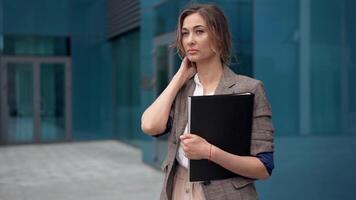 un mujer en un negocio traje participación un carpeta video