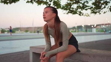 kondition kvinna i sporter ha på sig håller på med lunges på steg, och stretching ben på sommar parkera nära havet. video