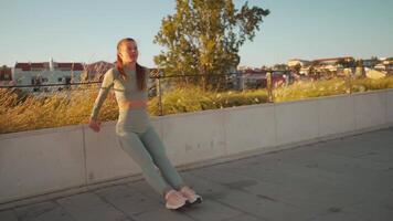 Fitness woman in sports wear doing lunges on step, and stretching legs on summer park near seaside. video