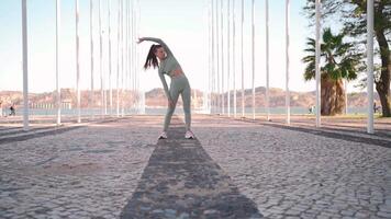 ginástica mulher dentro Esportes vestem fazendo investidas em etapa, e alongamento pernas em verão parque perto à beira-mar. video