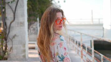 une femme dans des lunettes de soleil et une floral chemise des stands par le océan video