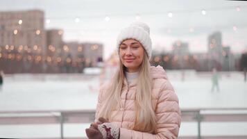 a woman in a pink coat and hat is standing on an ice rink video