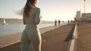 Young adult fitness woman jogging by embankment area coastal city in beautiful sunny day. video