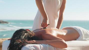mulher desfrutando profissional spa mão massagem deitado em especial mesa em de praia durante período de férias. massagem terapeuta dando relaxante massagem do cliente braços e ombros video
