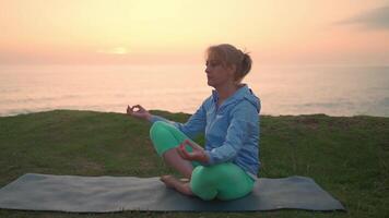 senior kvinna praktiserande yoga övning på de strand. video