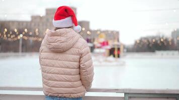 un' donna nel un' rosa cappotto e cappello è in piedi su un ghiaccio pista video