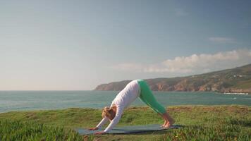 mayor mujer practicando yoga ejercicio en el playa. video