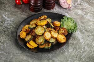 Roasted young zucchini in the plate photo